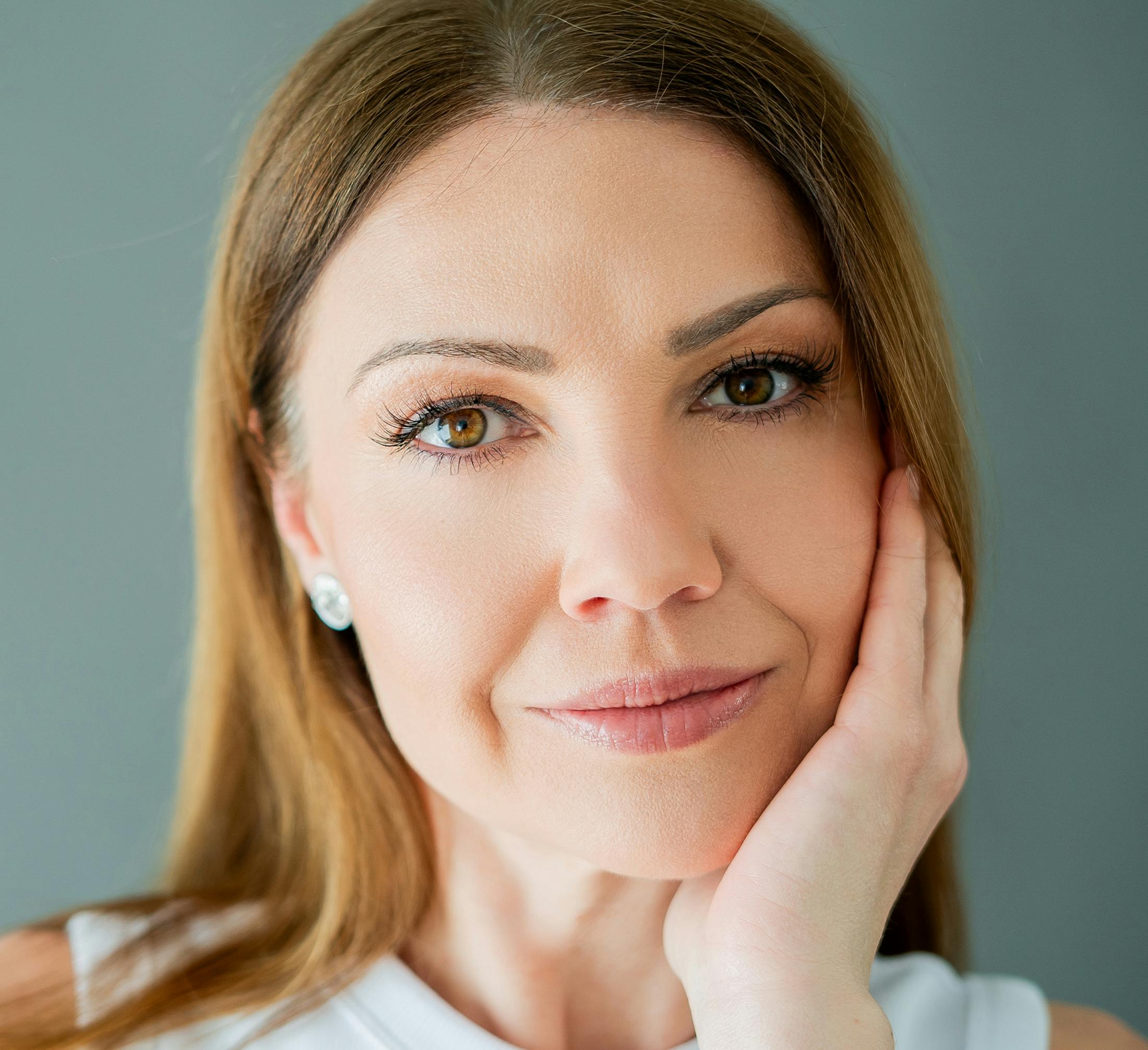 blonde woman with straight hair and hand placed on her jaw