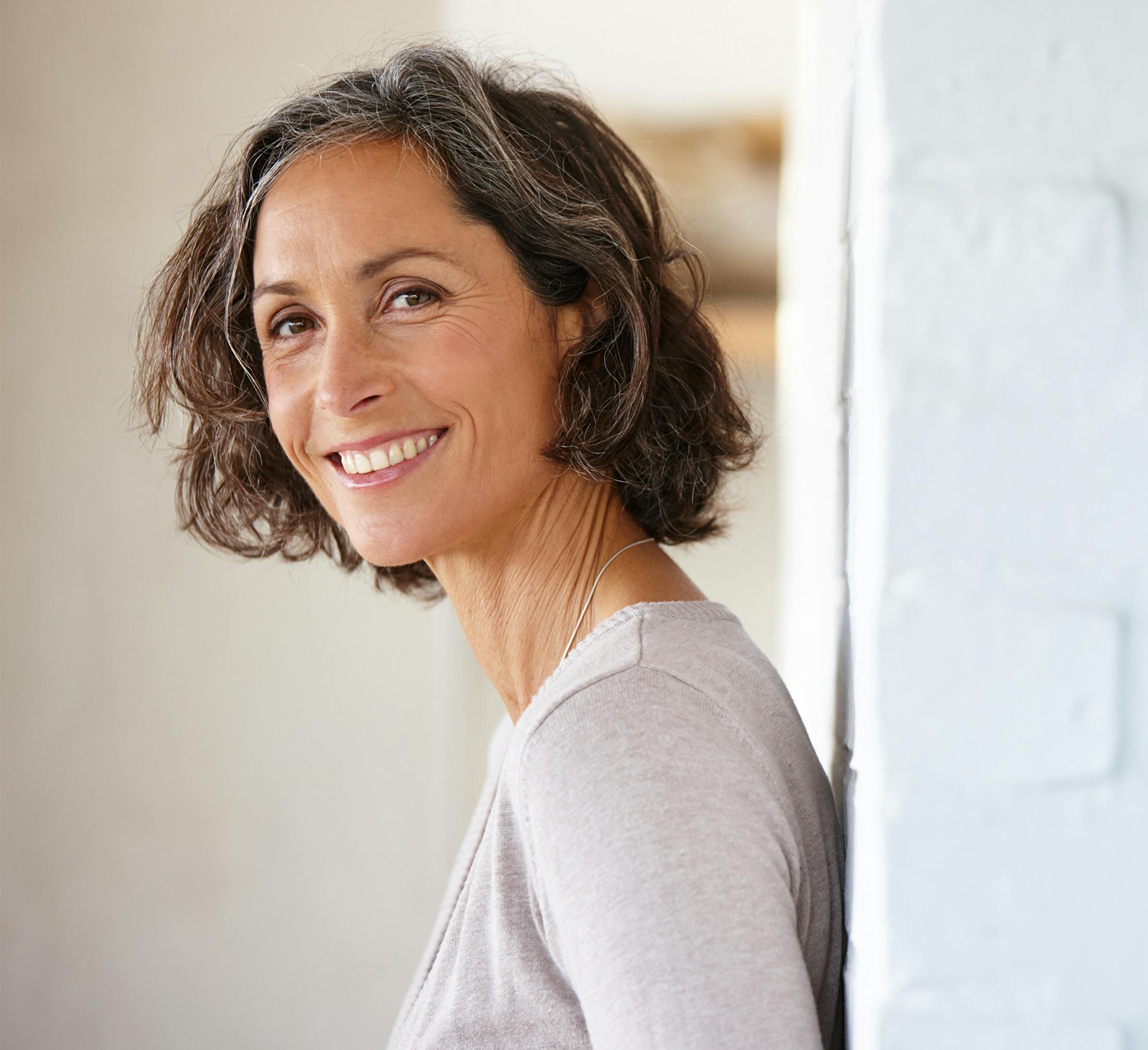 woman with short bob standing against white brick wall
