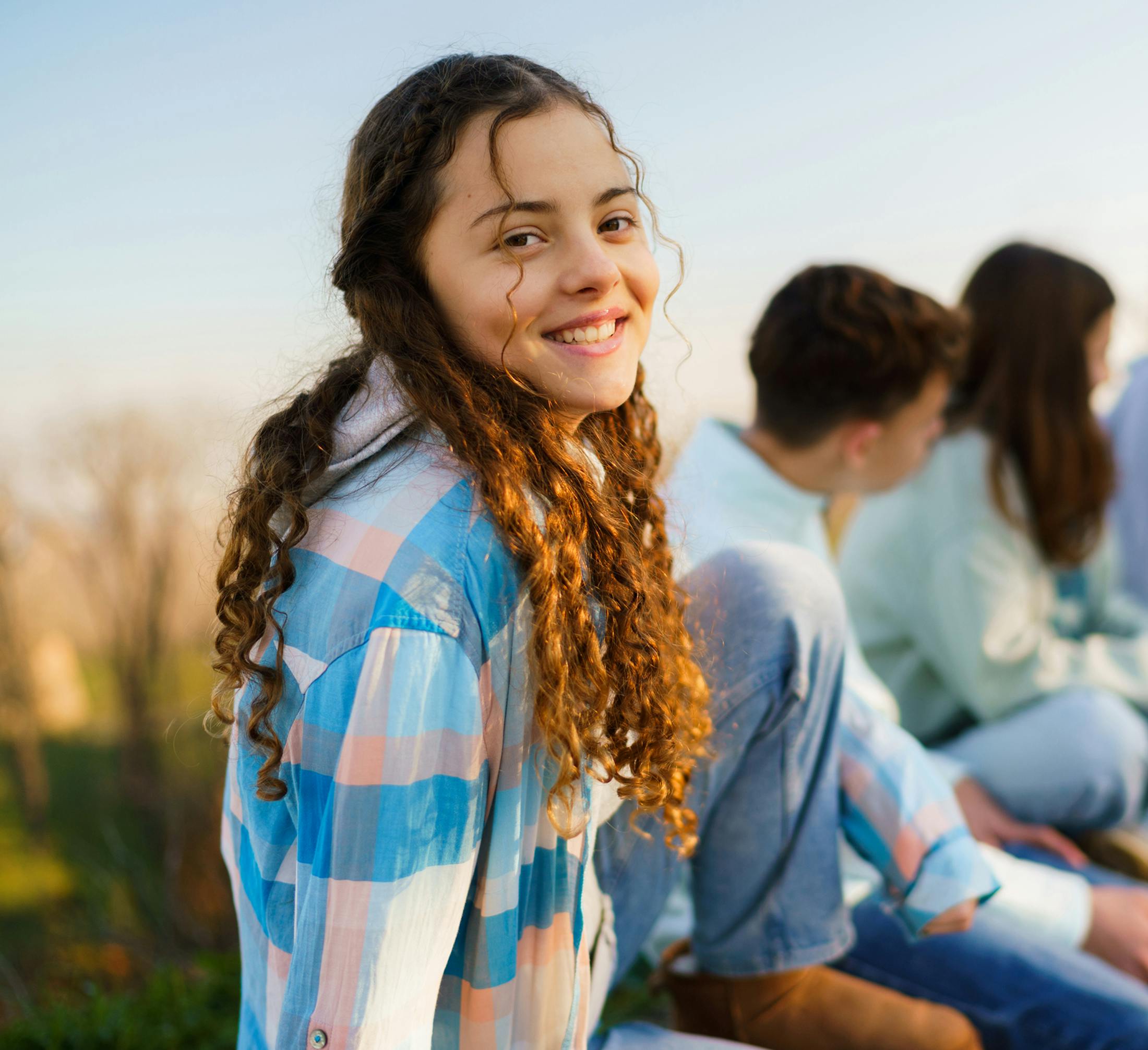 teen girl with long curly hair and checkered pink and blue shirt