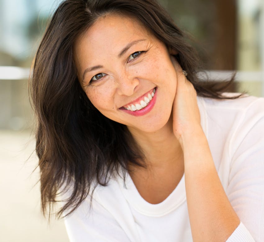 woman with hand on neck wearing white shirt
