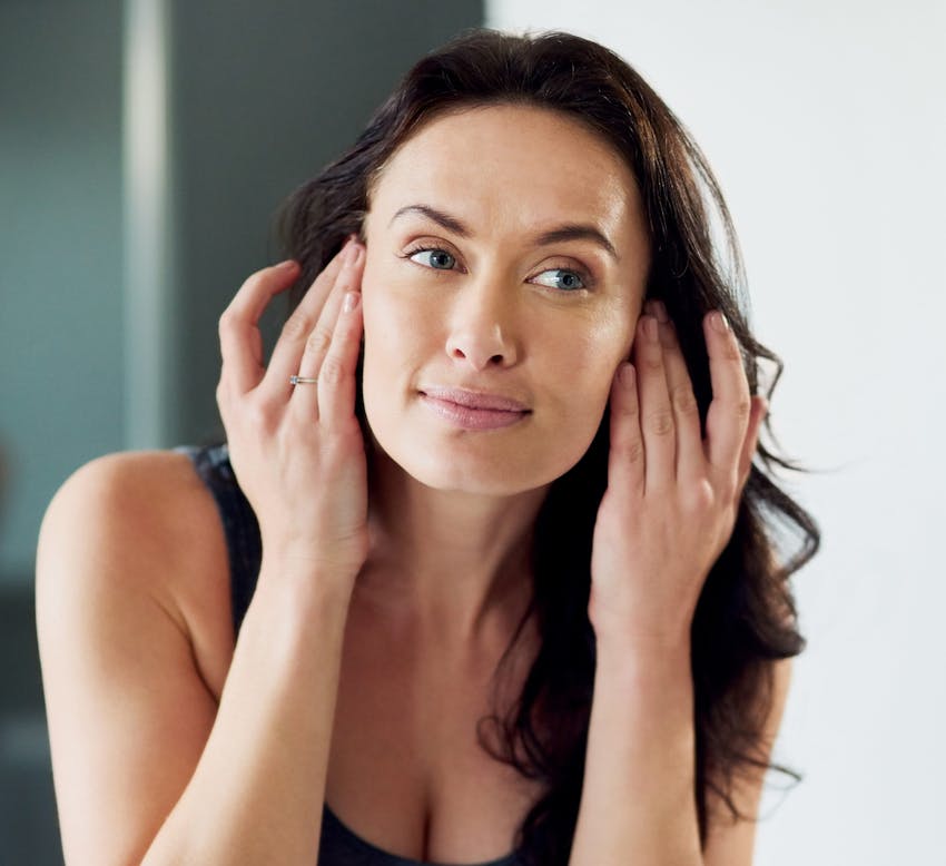 woman with dark curled hair touching her temples