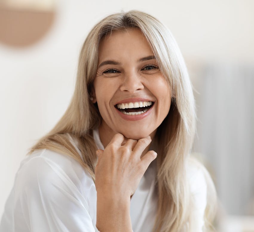 woman laughing with hand on her chin and white shirt