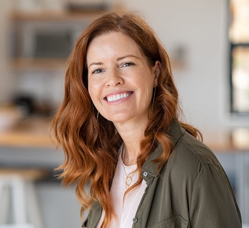 red haired woman wearing green blouse and white shirt looking forward