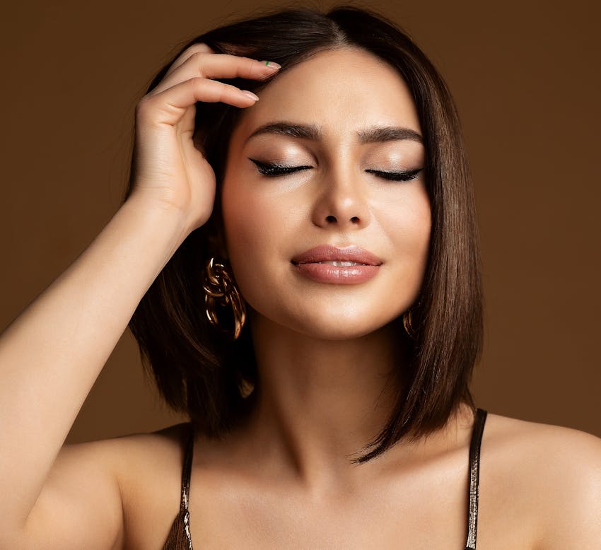 woman with short brown hair holding her hair away from the face