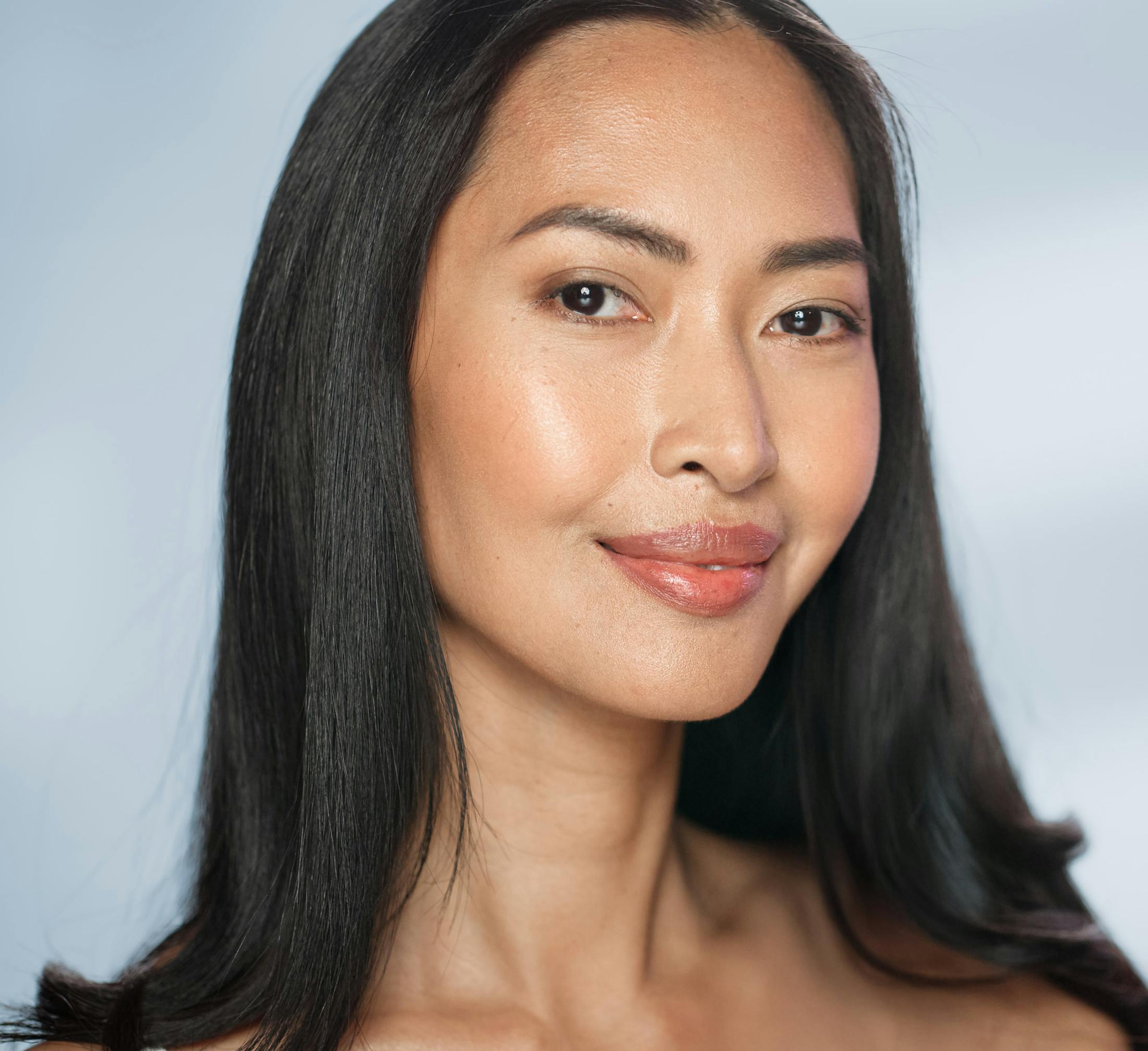 woman with glowy skin and black hair looking at the camera