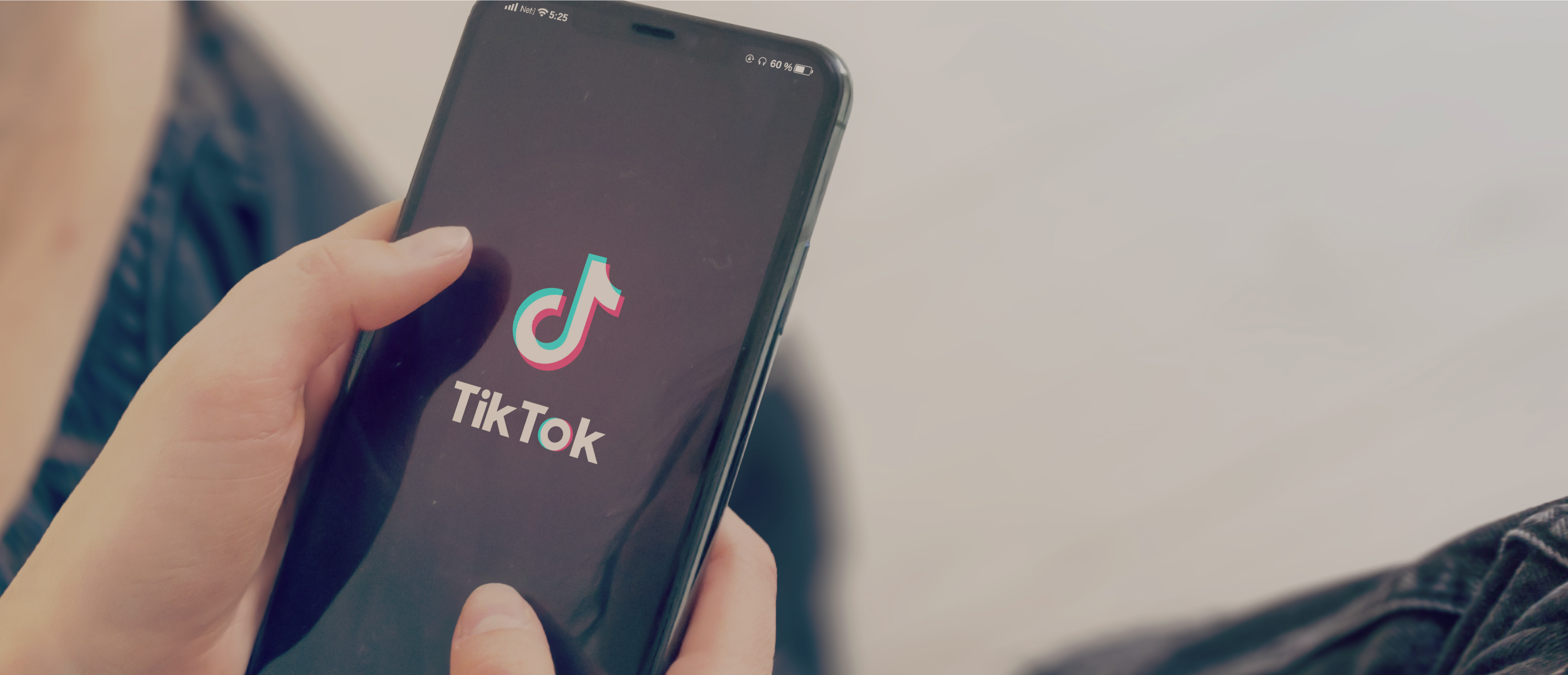 Integracja IdoSell z TikTokiem Kobieta trzymająca smartfon z wyświetlonym ekranem z TikTokiem