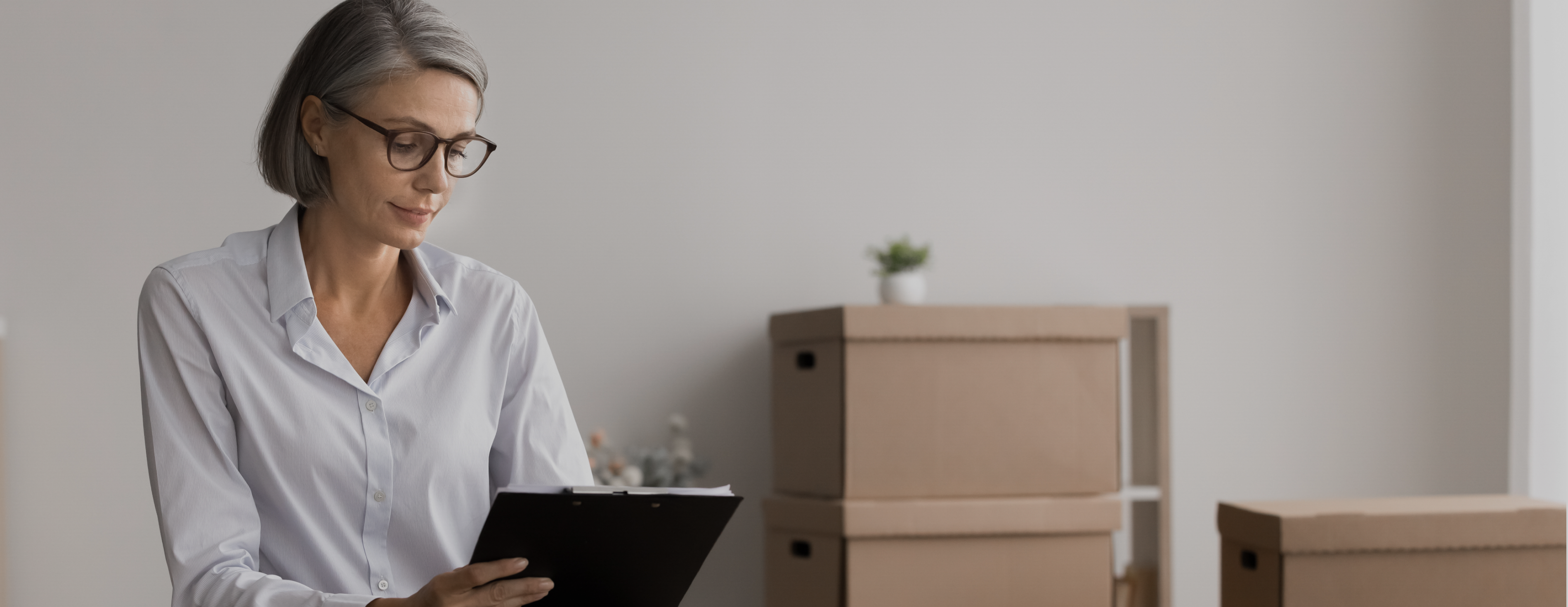 Kobieta robiąca notatki na tle zapakowanych kartonów