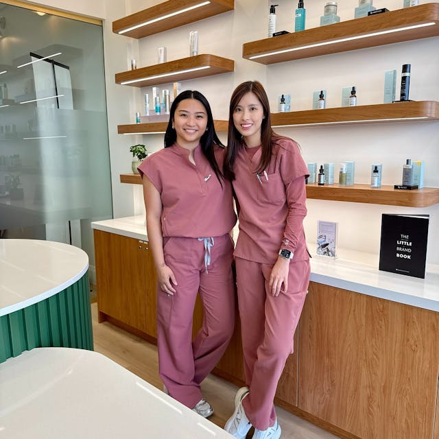 Two nurses smiling and leaning against reception desk