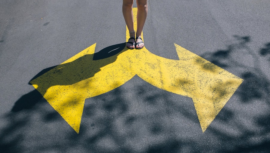 An image of a person standing at a painted crossroads on a road.