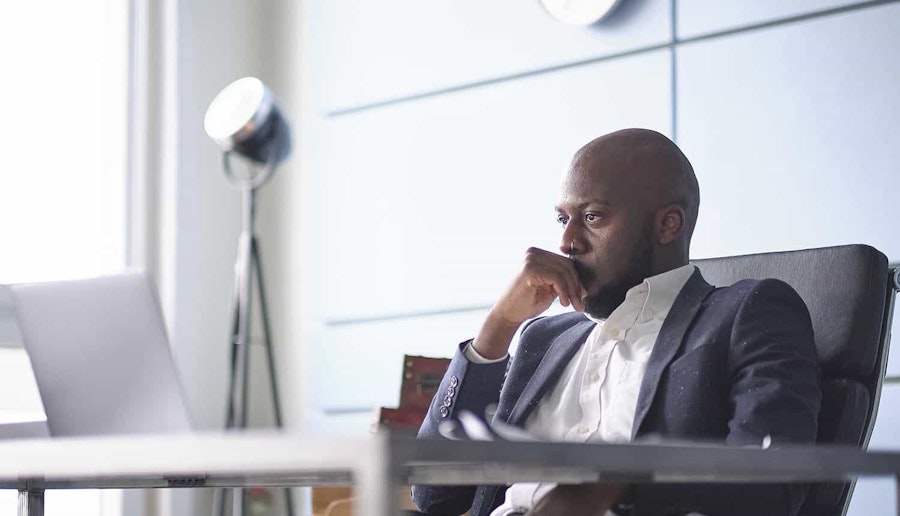 An image of a man sitting at a desk thinking.