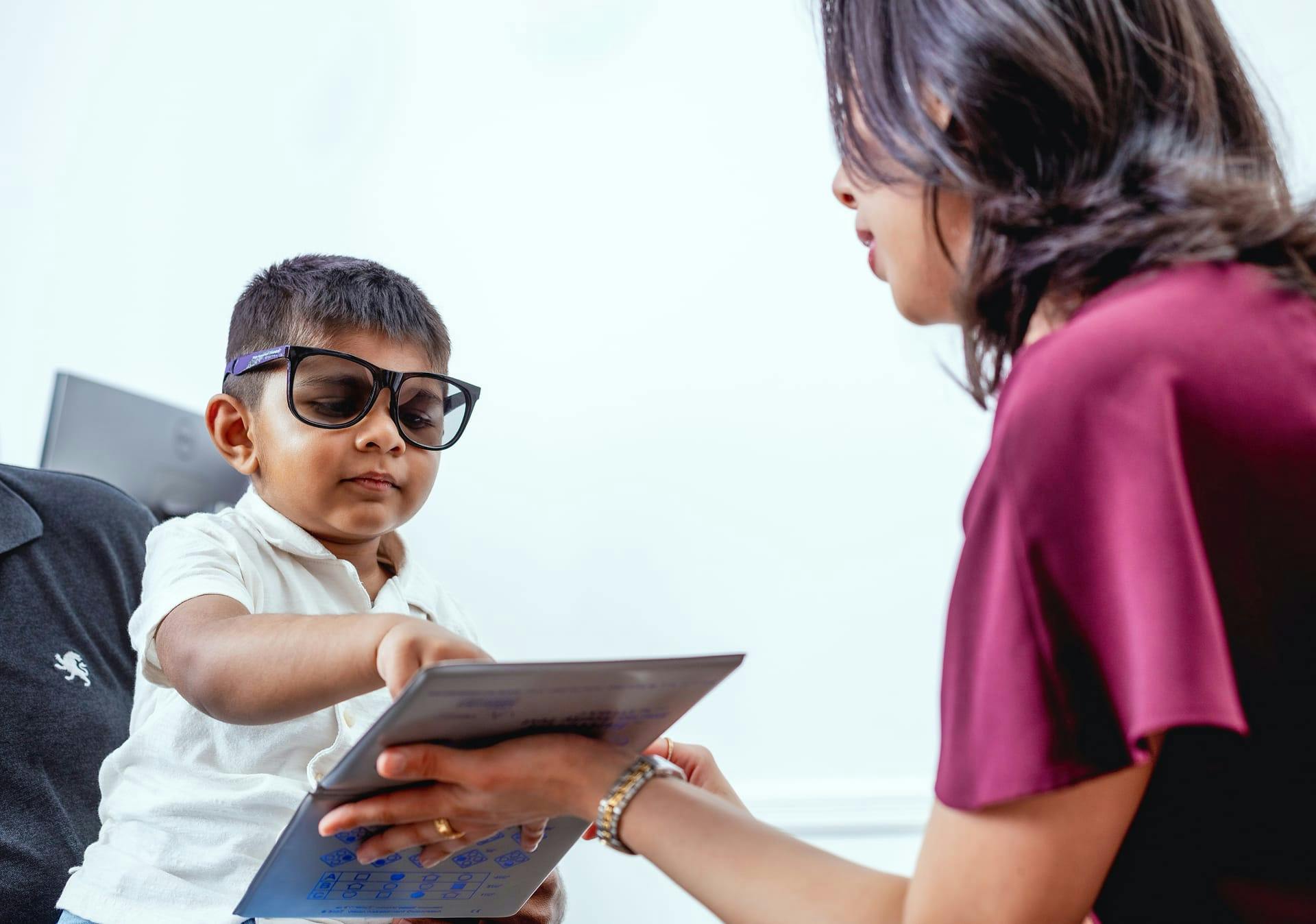Kid pointing to a book during eye exam