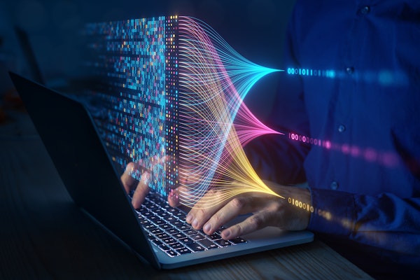 Person working on a laptop with colourful holographic data streams and binary code visualizations symbolising big data analysis and machine learning.