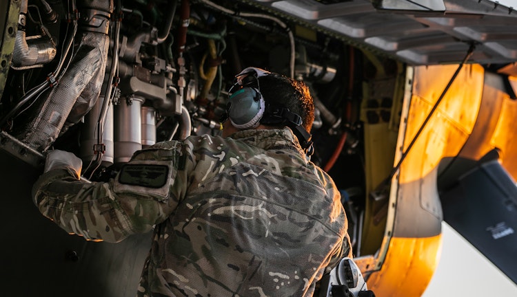 Military ground engineer inspecting and working on the engine components of an aircraft.