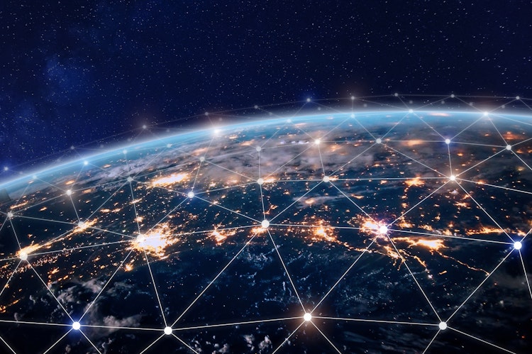 Digital illustration of Earth at night with glowing city lights and an interconnected network grid overlay, symbolising global communication and internet connectivity.