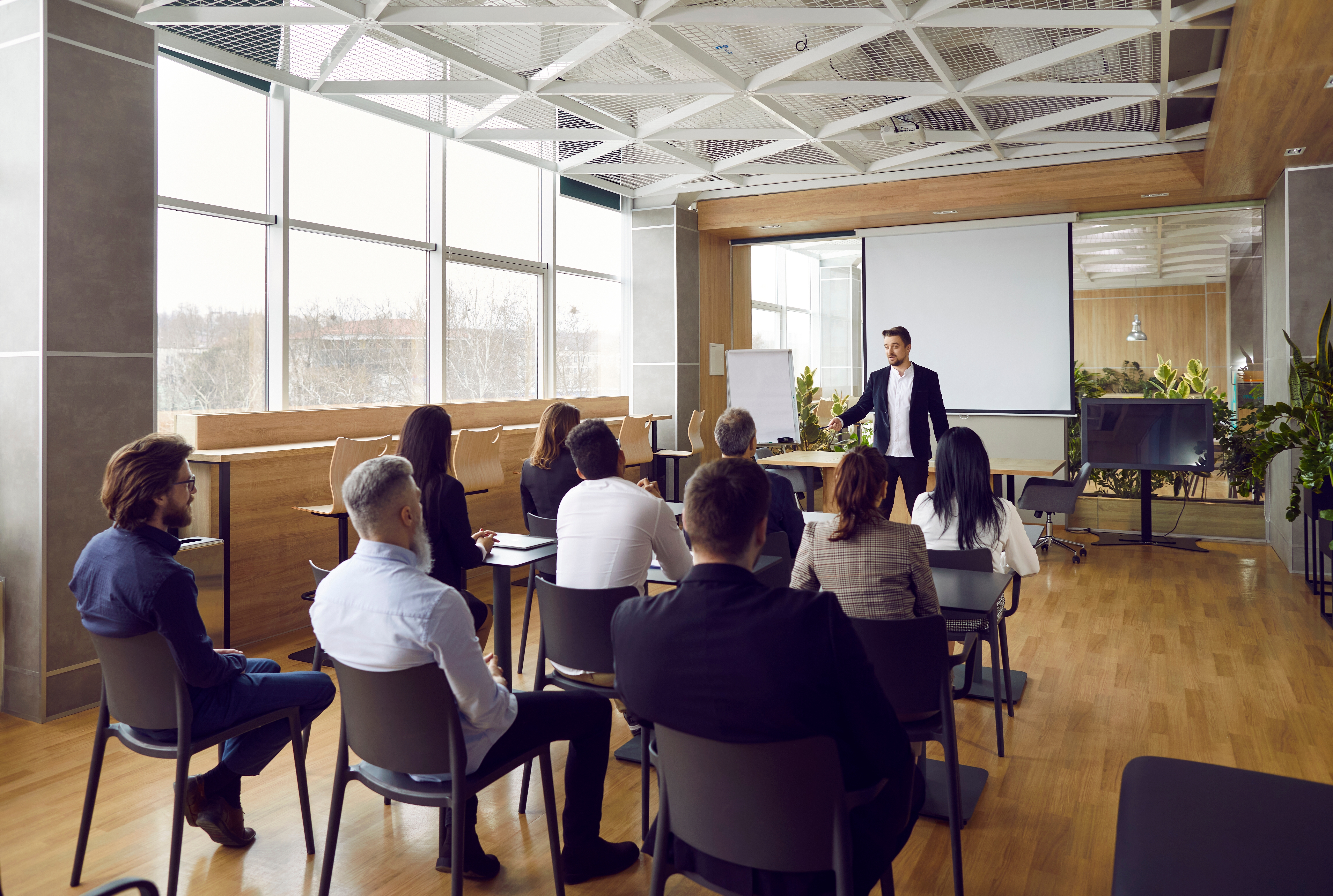 Business professional giving a presentation to a seated group in a modern conference room.
