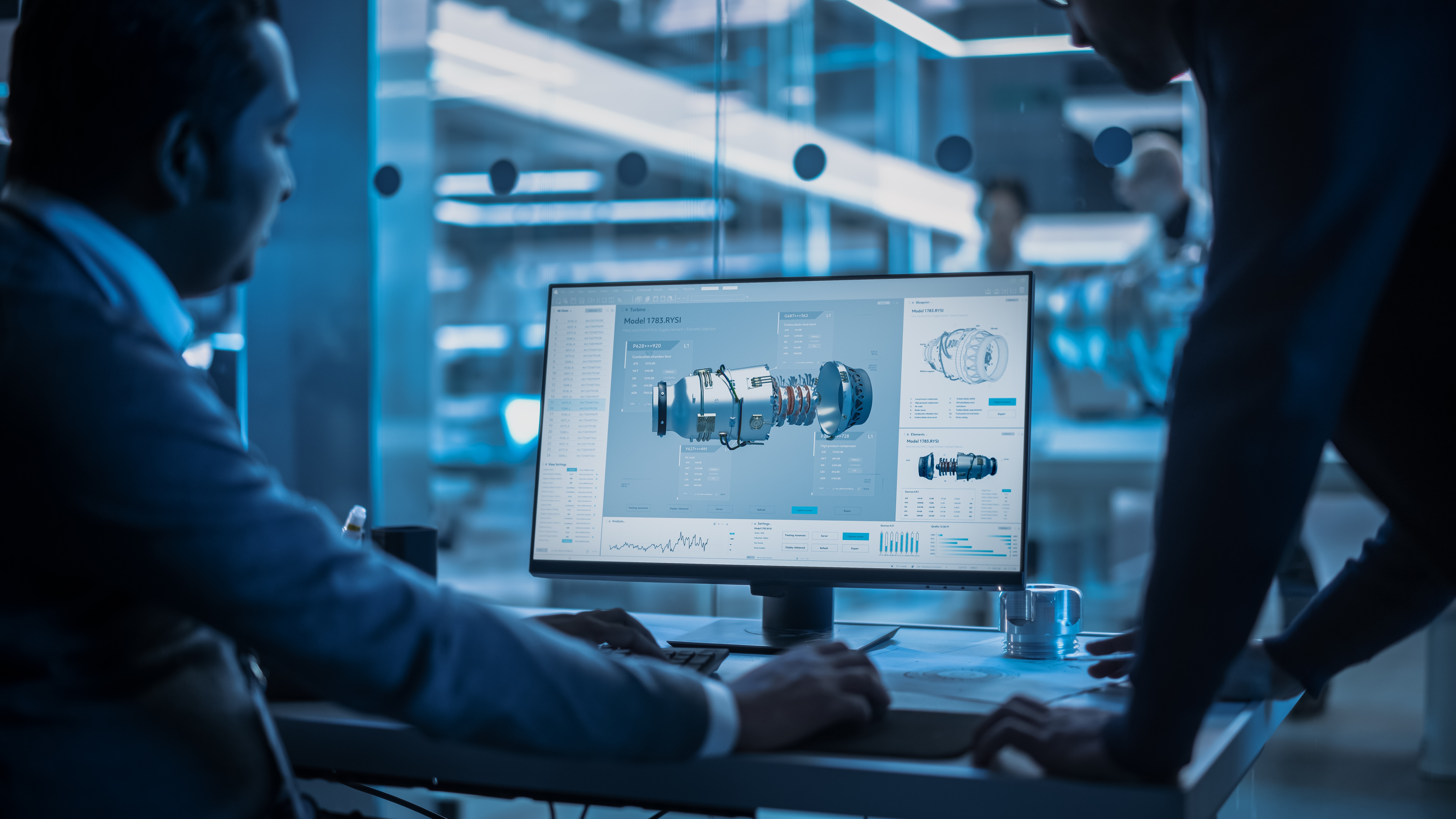 Engineers reviewing a 3D CAD model of a turbine component on a computer screen in a modern high-tech office.