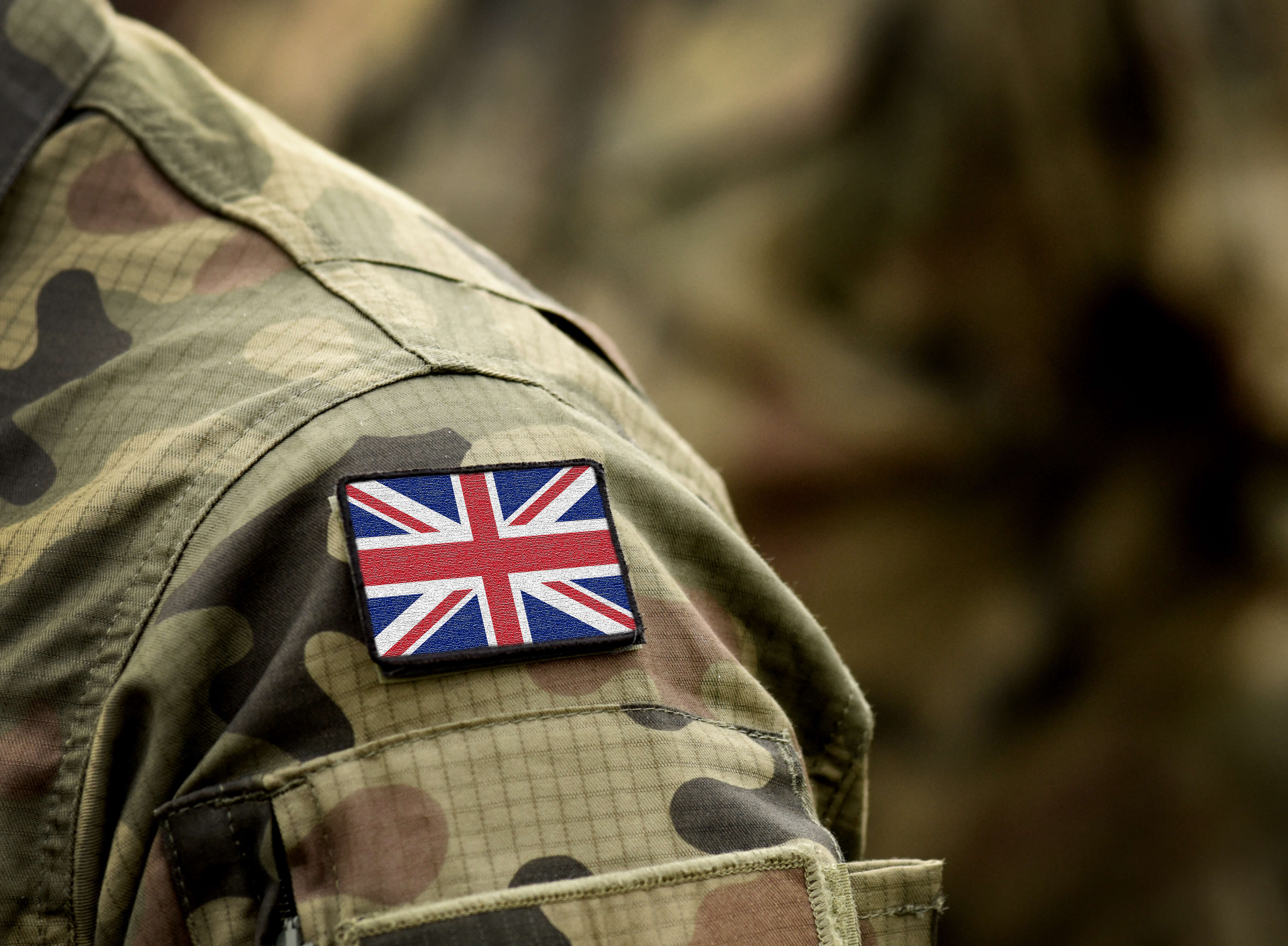 Close-up of a soldier’s camouflage uniform with a Union Jack patch on the shoulder.