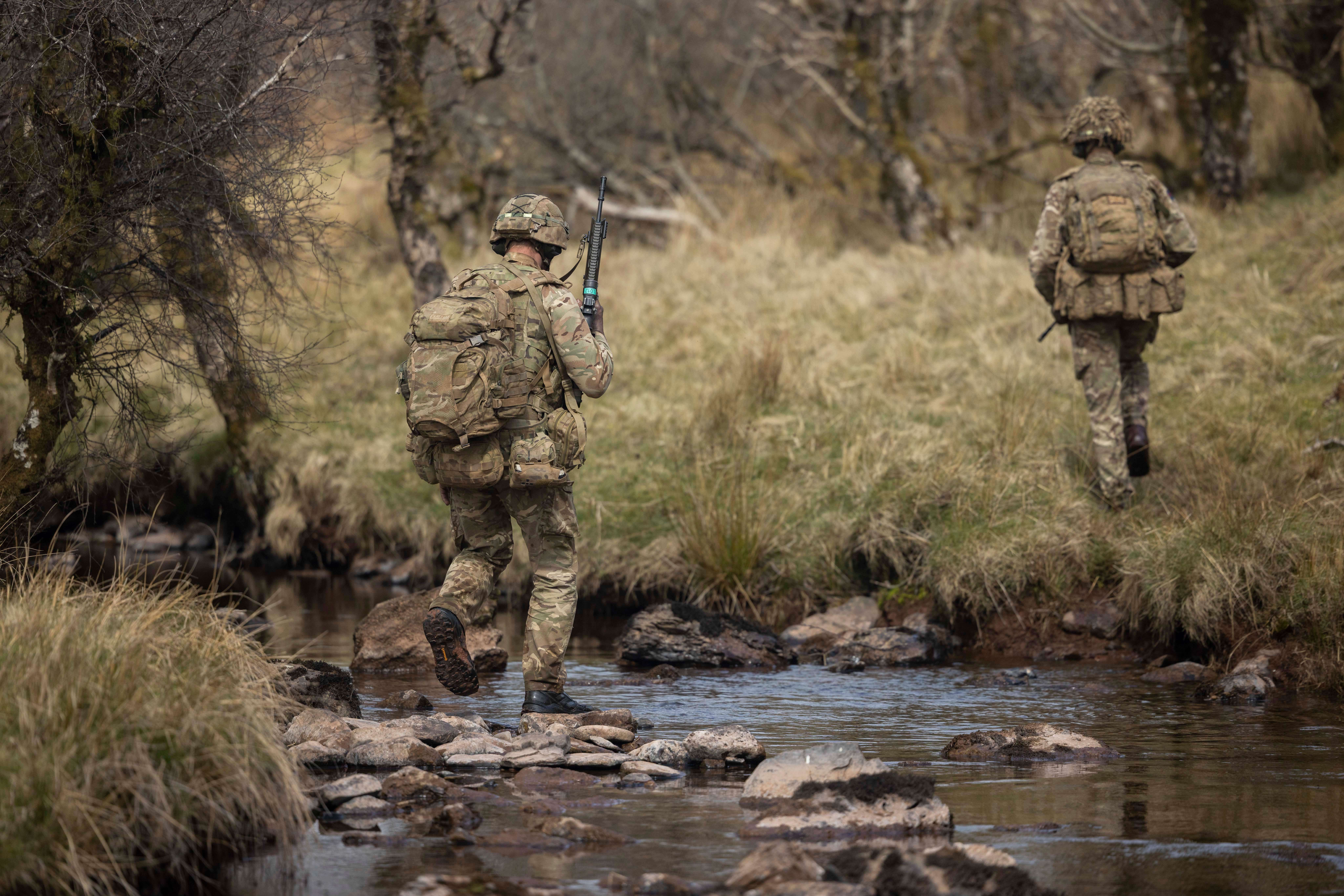 Two soldiers walking through a river.