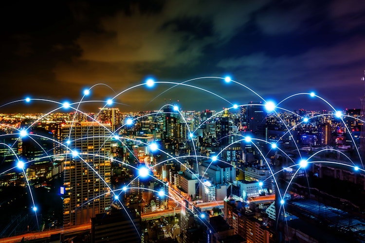 City skyline at night with glowing digital network connections overlay, symbolizing smart cities and global connectivity.