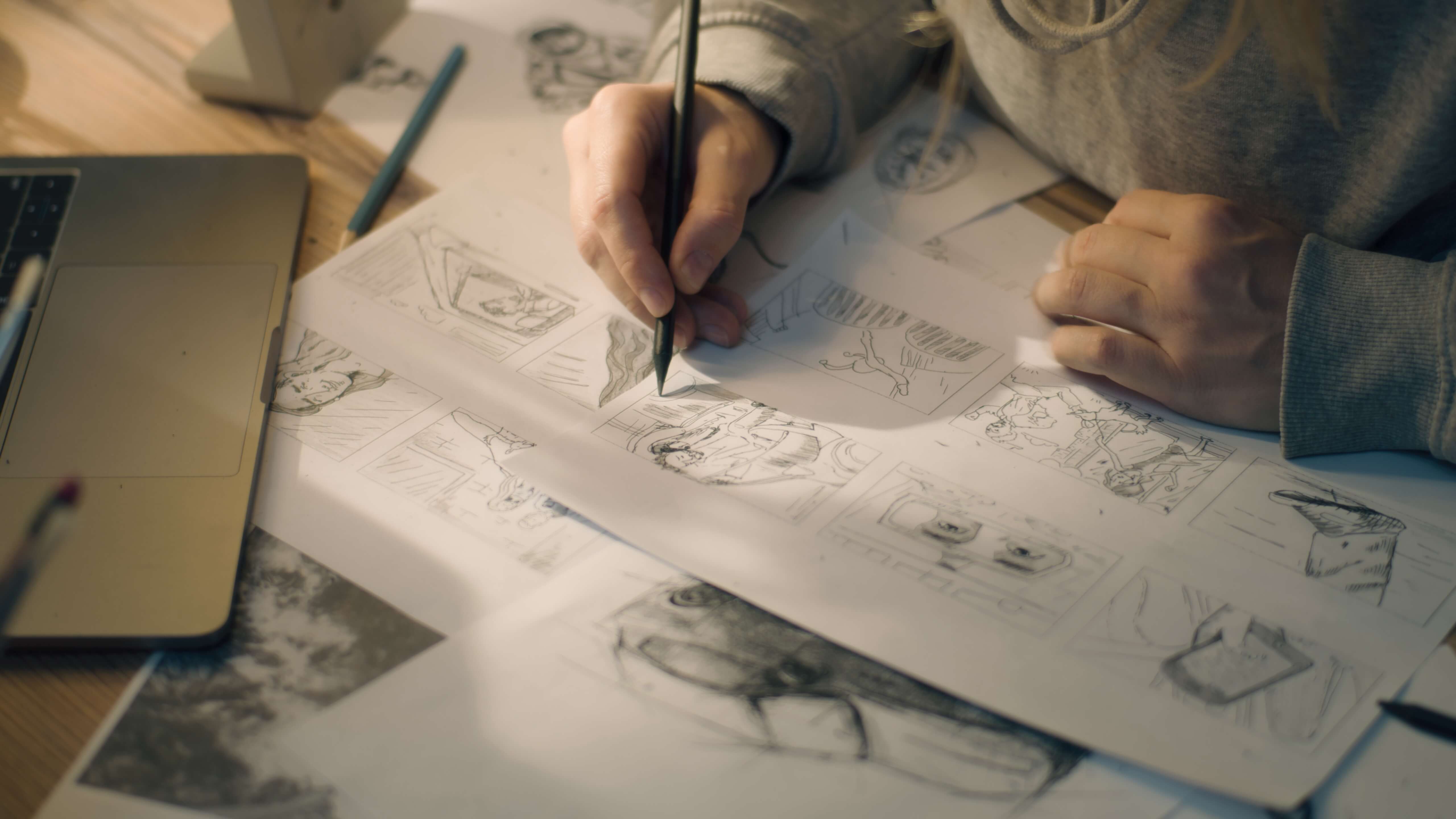Artist sketching storyboard panels by hand on a desk.
