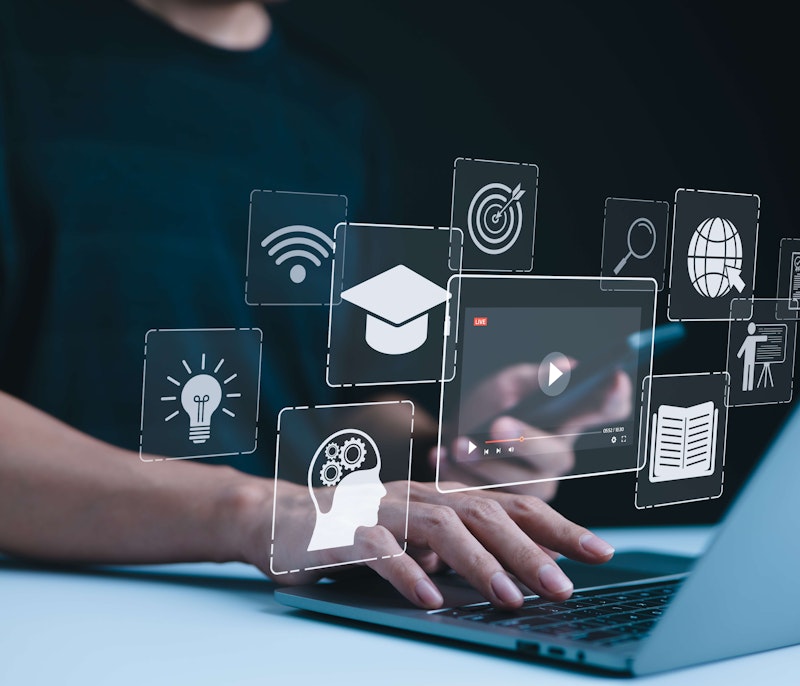 Person using a laptop with floating digital icons representing online learning and innovation.