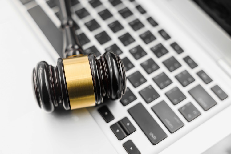 Judge’s gavel resting on a laptop keyboard, symbolizing digital law and cyber justice.