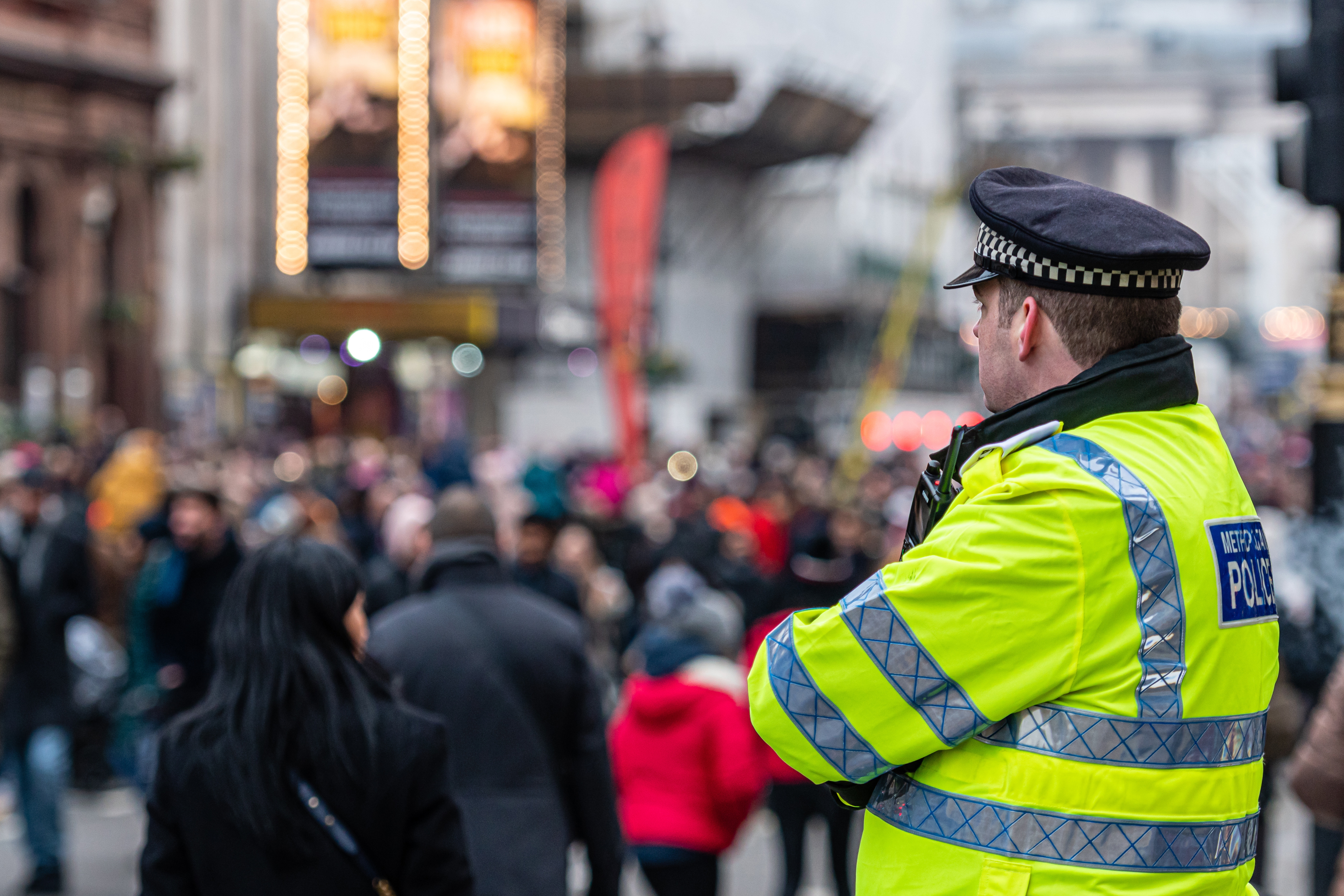 Police officer in yellow uniform watching crowd of shoppers
