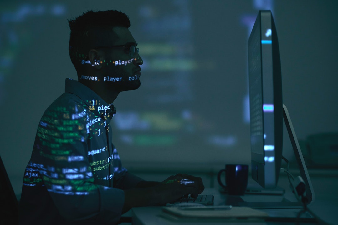 technology agnostic male using computer with data / code overleyed on top