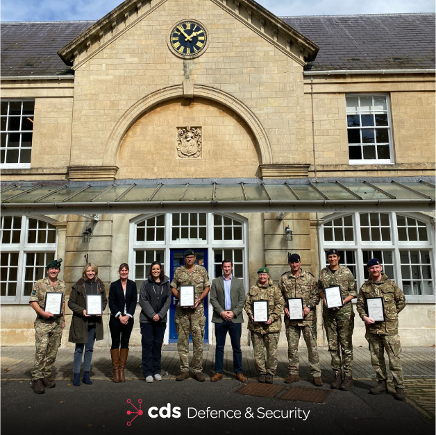 CDS DS trainers in front of sandstone building, joined with Lt Col Steve OCock RIrish - COS AOSB, Caroline West - Supervising Officer AOSB, Natalie Chadwick - CDS DS (Contractor), Vicki Smith - Transcend Awards, Col Iain Moodie - President AOSB, Rod Bell - CDS DS, Lt Col Susie Castle-Smith - AGC(SPS) AOSB Training Officer, Capt Ben Griffiths - RA Group Leader, Maj Tara Sugden - AGC(ETS) Education Advisor, Capt Freddie Phipps - RLC Group Leader