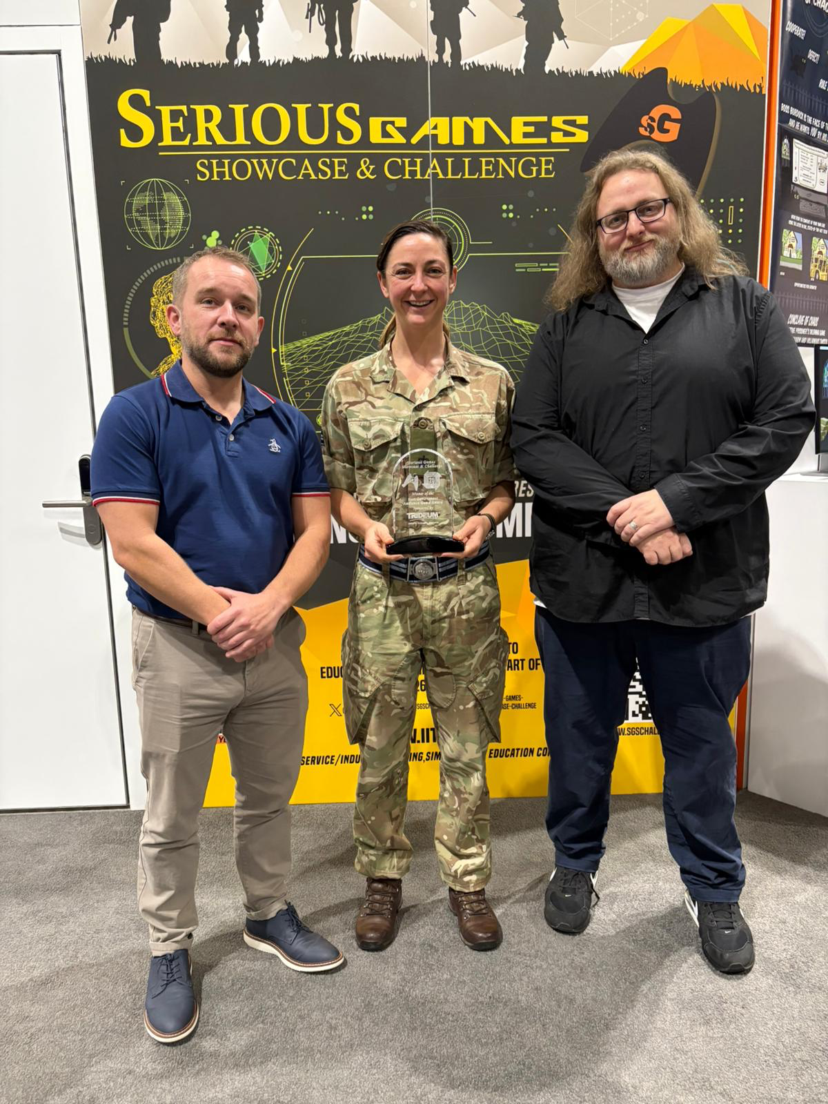 CDS DS employees John Dagger & austen shand along with Major Amanda Willcox-Jones with the Government audience award in front of serious games banner