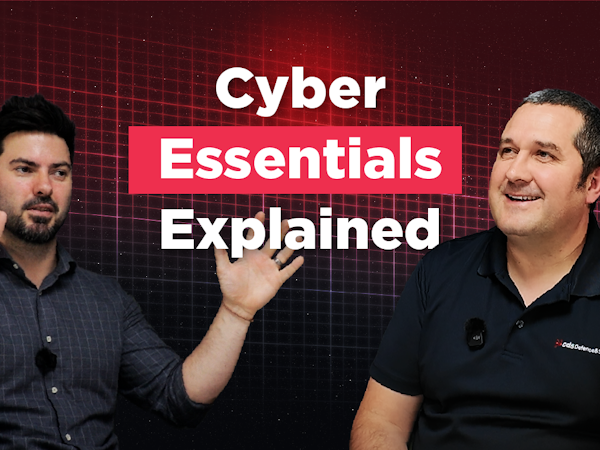 Cyber Essentials Podcast Thumbnail image for a podcast or video episode titled “Cyber Essentials Explained.” Karl Rees is pictured on the left wearing a dark blue shirt and gesturing with both hands while speaking. Michael Daly is pictured on the right wearing a black CDS Defence & Security polo shirt, smiling towards Karl. They are seated against a dark red digital grid background with large white and pink text displaying the episode title.