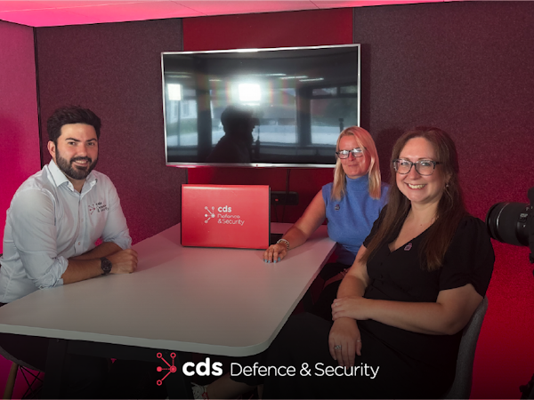 CDS DS Demystifying Cyber Podcast Episode Promotional image for the CDS Defence & Security Demystifying Cyber Podcast, showing Karl Rees seated at a table with two female podcast guests Helen Pierce and Channelle Smyth in a red-lit studio. A CDS Defence & Security branded laptop sits on the table, with a camera visible in the foreground.