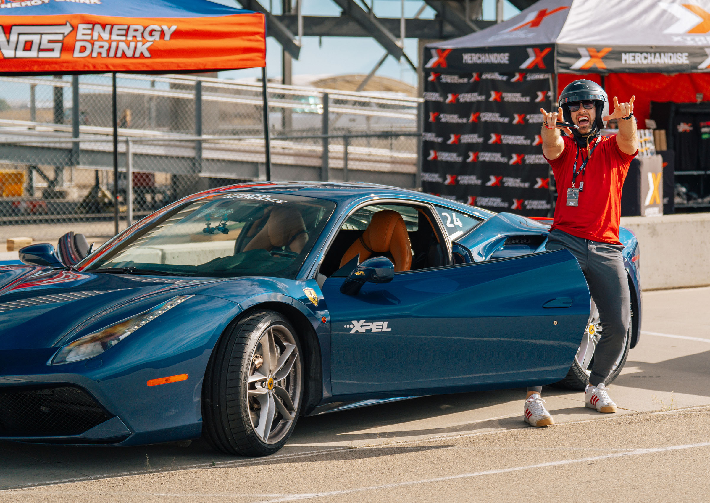 Man with his hands pointed at the camera with excitement in front of a blue Ferrari 488 GTB as he just completed his drive with Xtreme Xperience