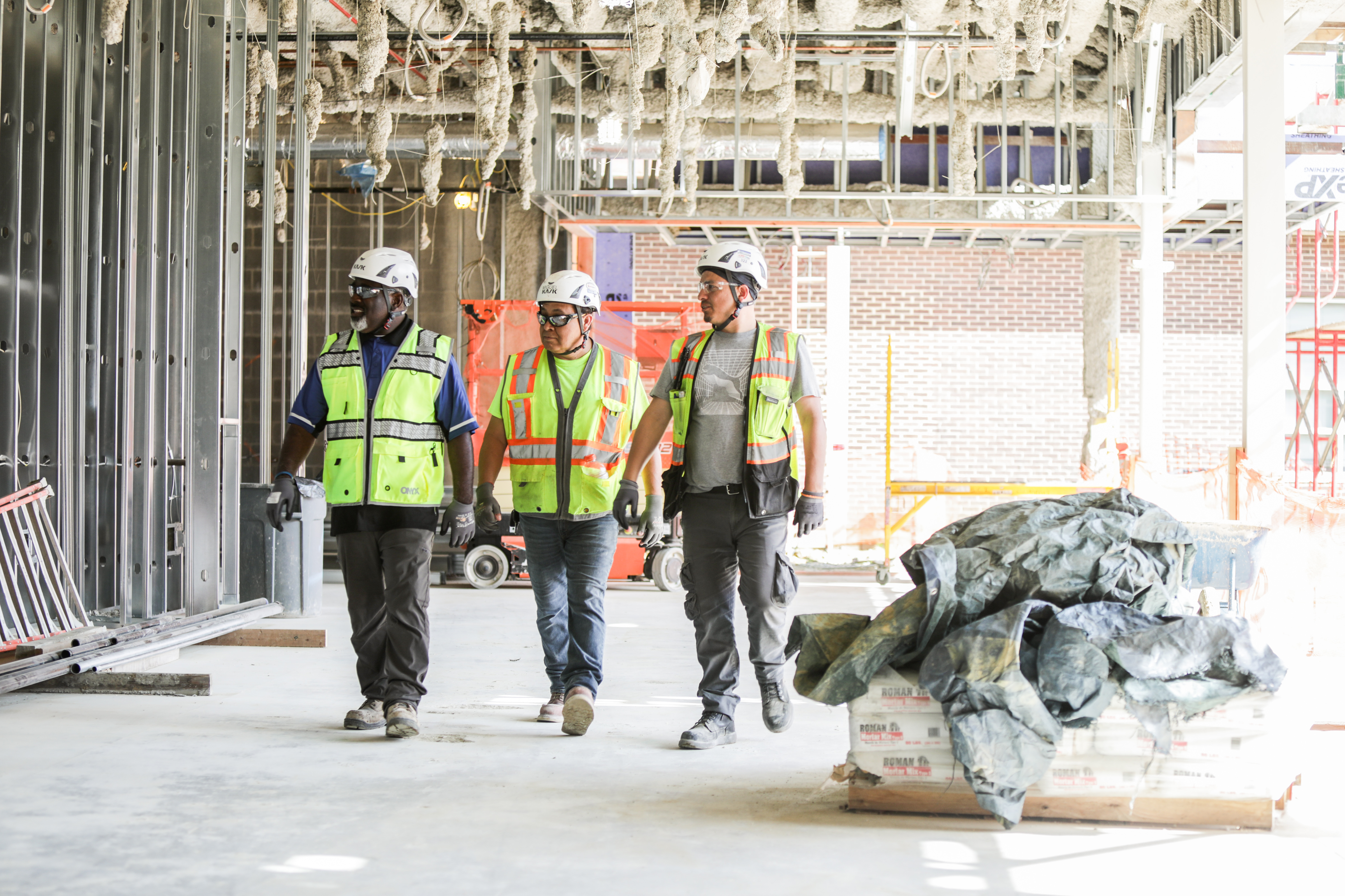 Three construction workers walking on construction site