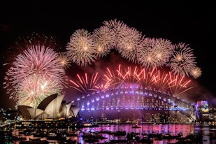 Fireworks explode from the arch of an illuminated Sydney Harbour Bridge with the harbour packed with spectator vessels. 