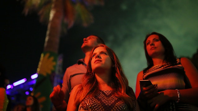 3 spectators look skyward during the New Year’s Eve fireworks display.
