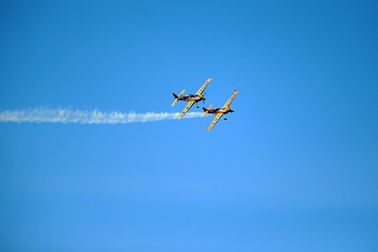 White smoke trails 2 single propeller aircraft in formation.
