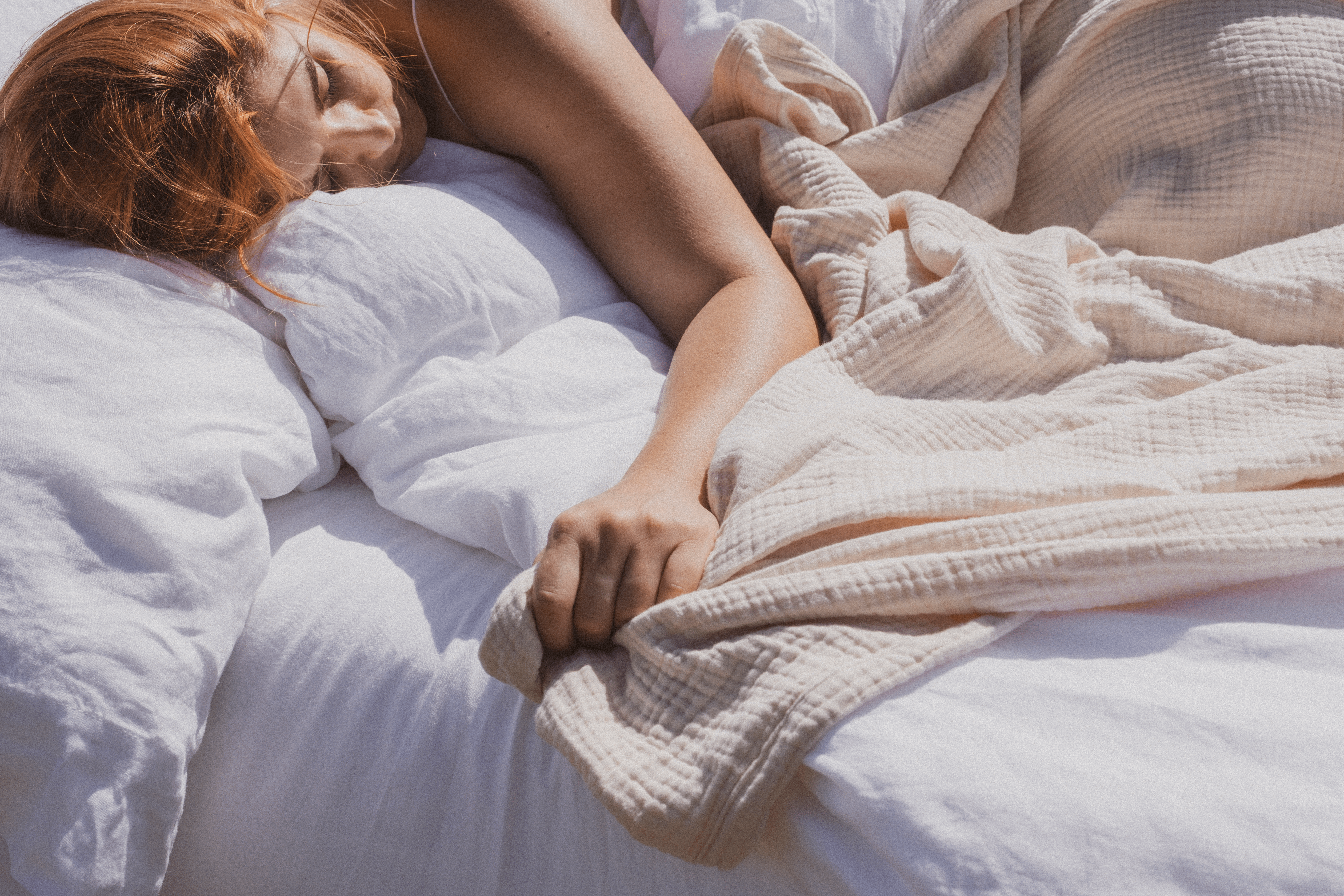 Woman laying in bed with blanket and sheets