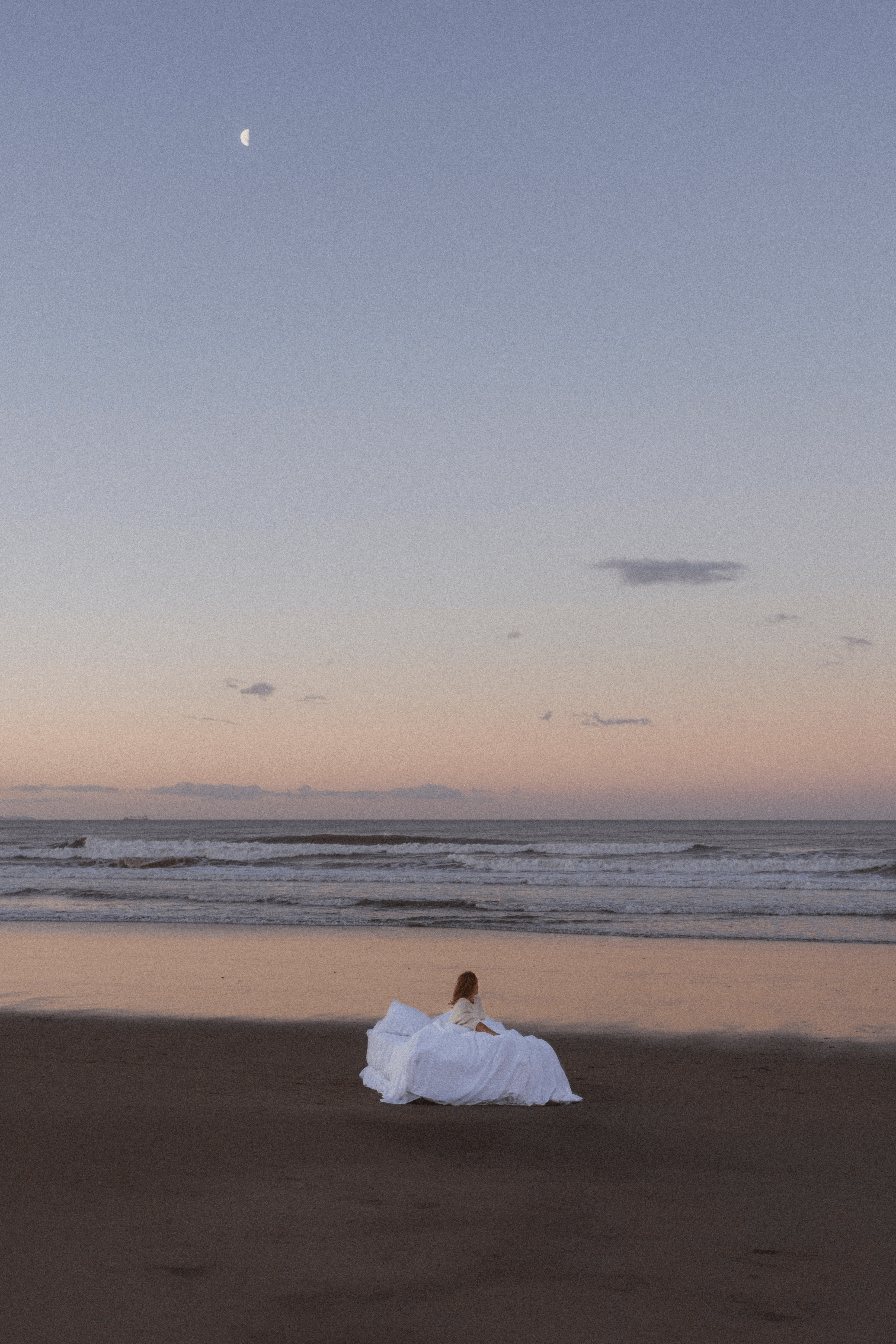 A woman on a bed on an empty beach