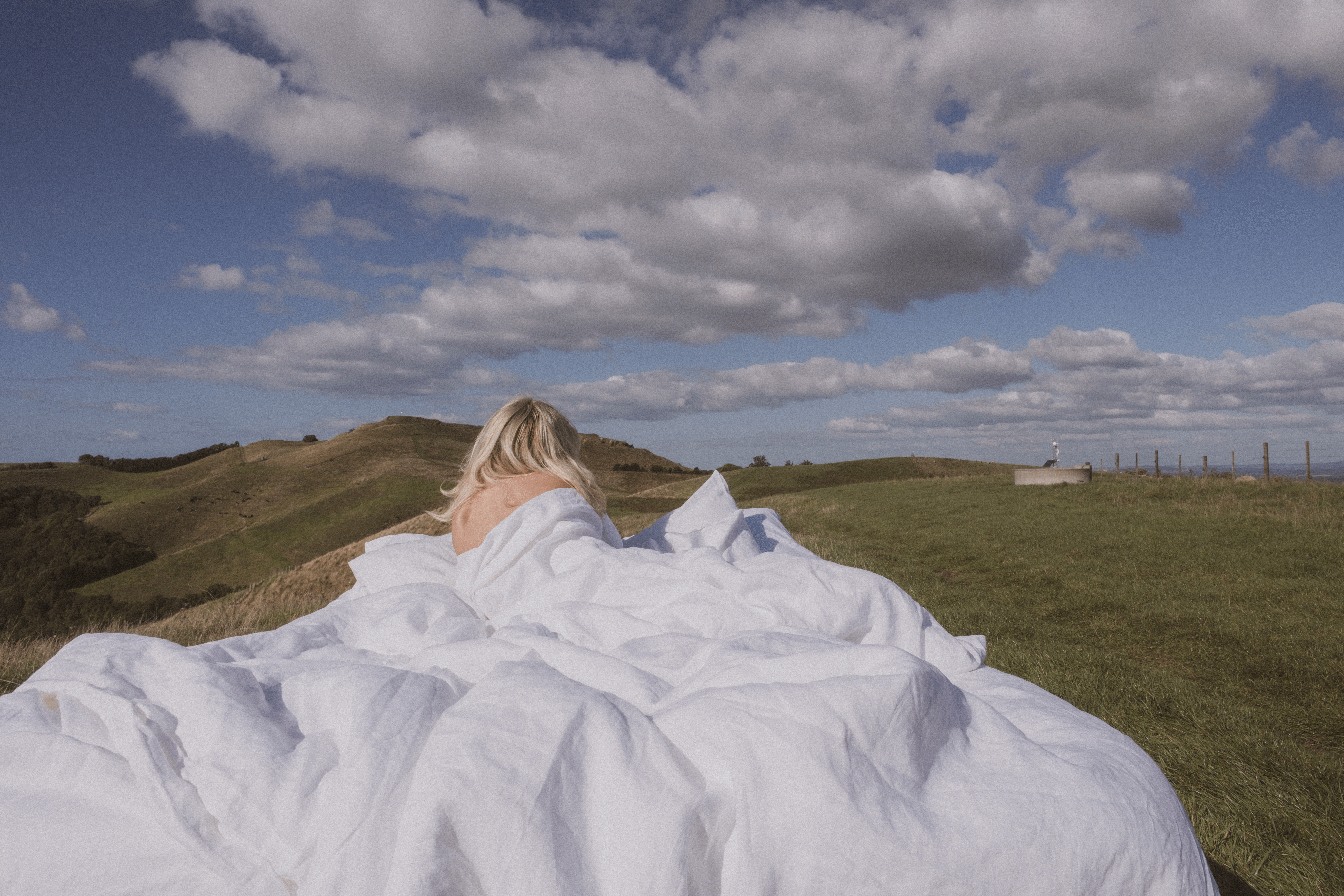 Woman laying in bed in the middle of a field