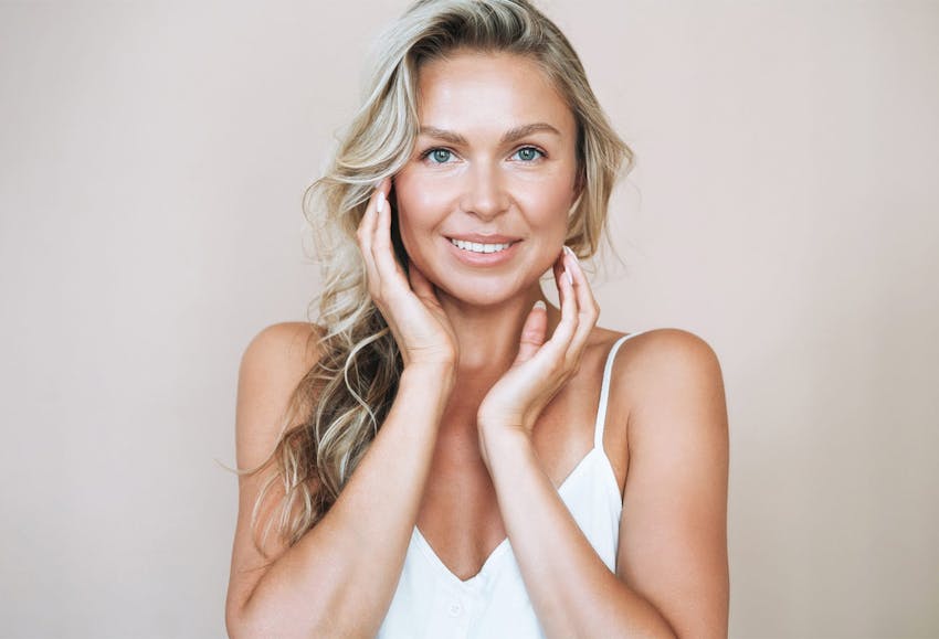 woman with blonde hair touching the sides of her face