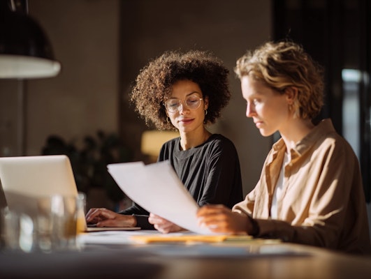 Two research professionals collaborating on project documents, representing MindMarket's dedicated project manager approach to global qualitative research