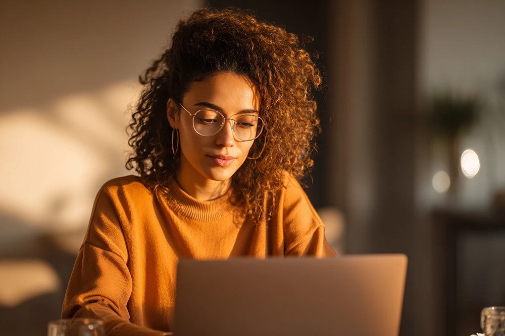 Woman using MacBook in warm natural light — Mac purchase UX research case study