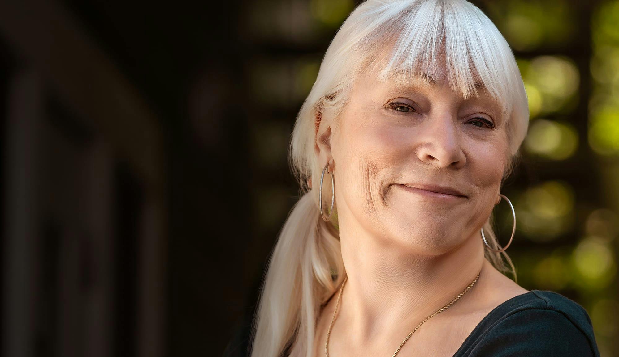 Smiling older woman with white hair representing face and neck treatments