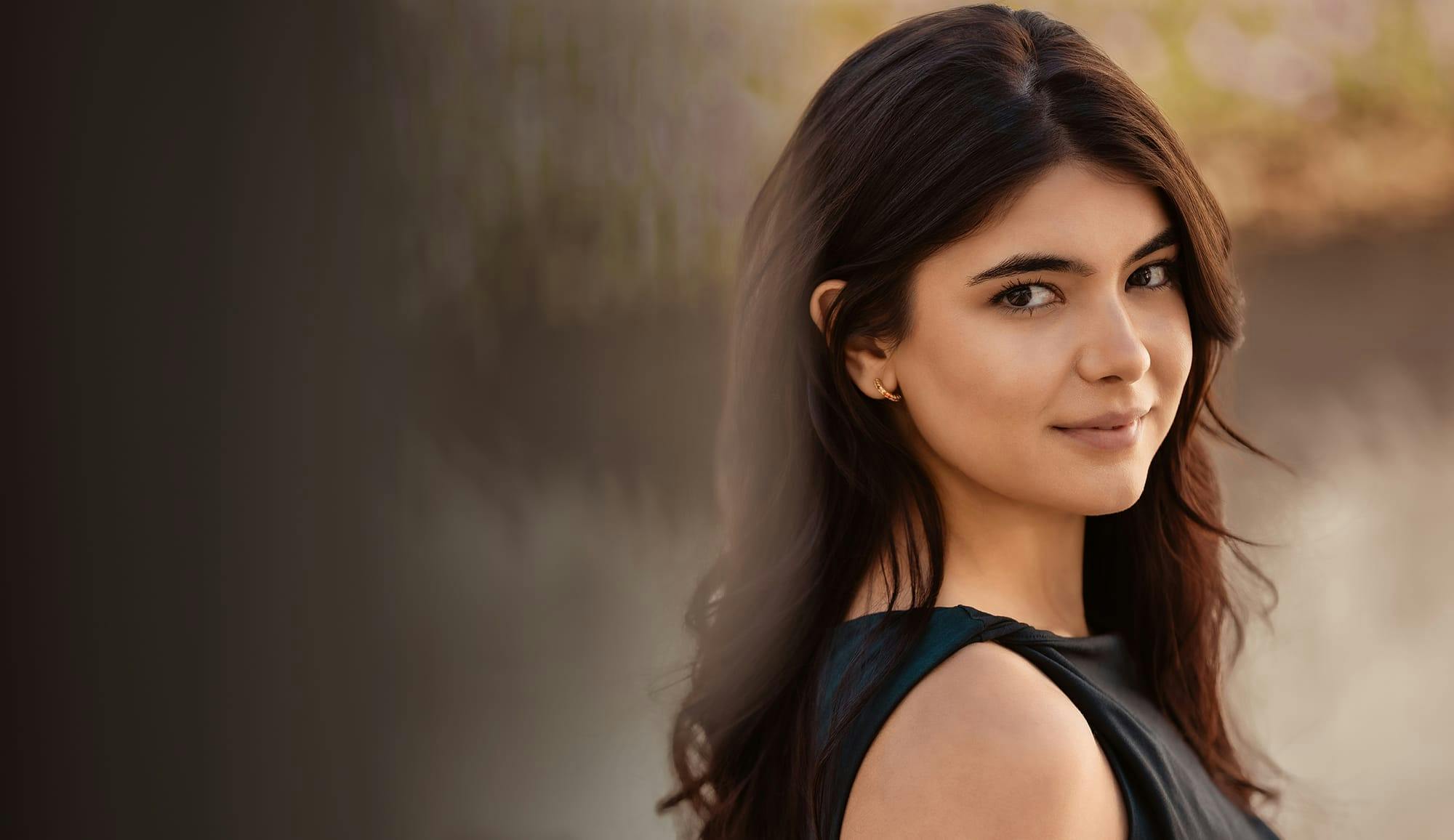 Woman with long dark hair looking at camera, representing injectable treatments