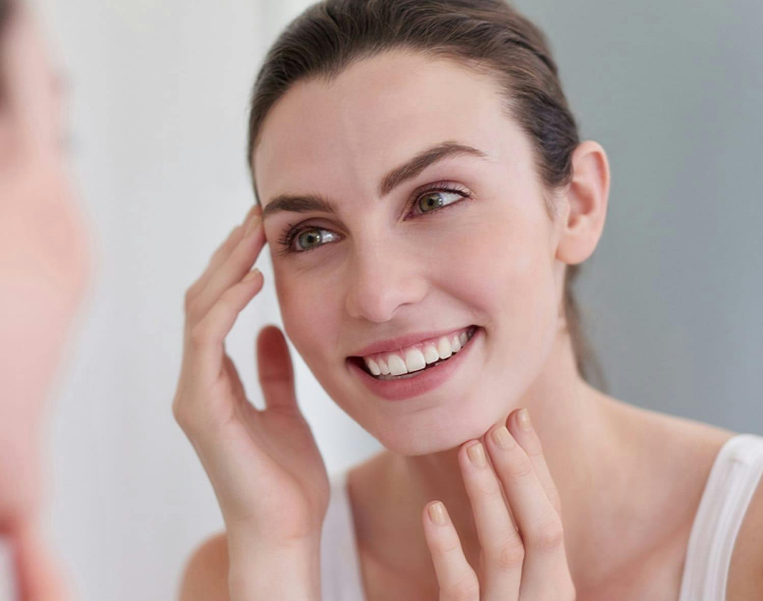 woman looking at her face in a mirror
