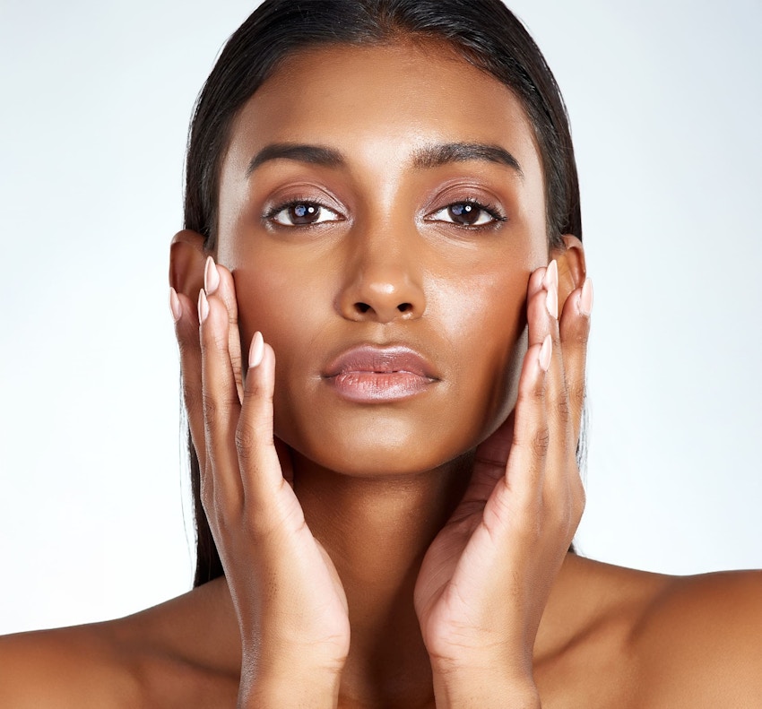 woman looking forward and touching her face