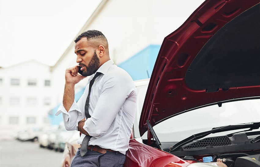 A man on the phone leaning on his car