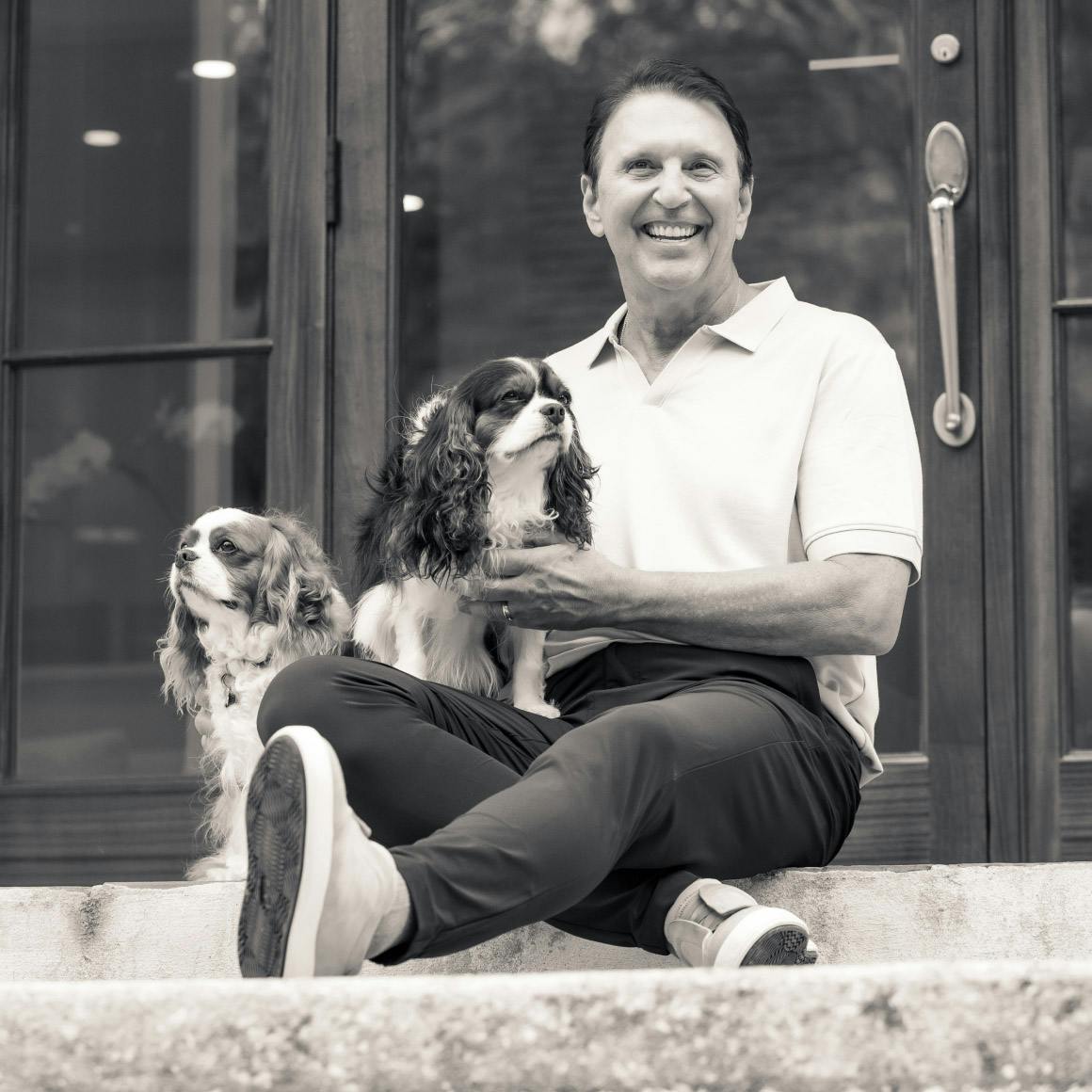 Dr. Rick sitting on stairs with his dog greyscale
