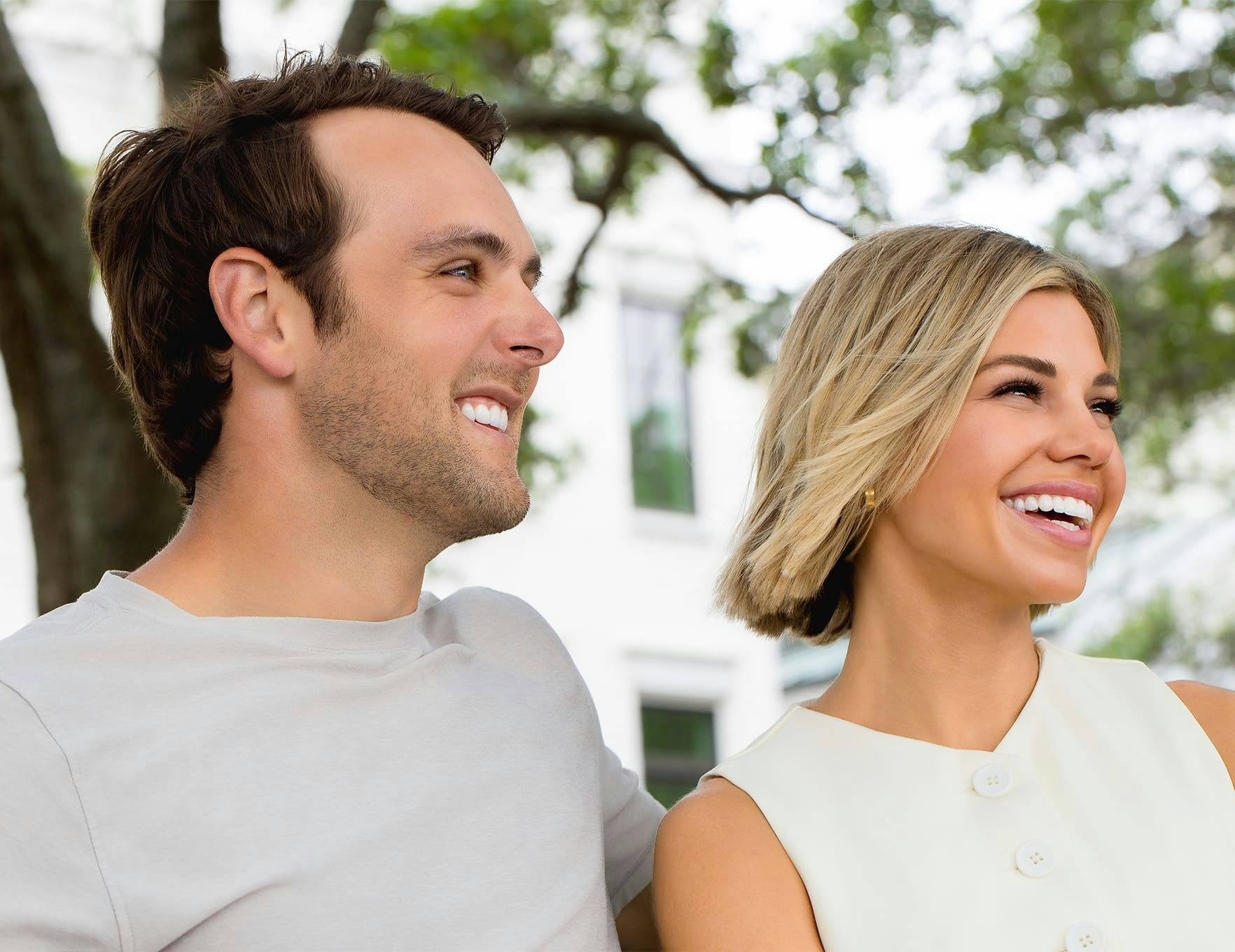 man and woman sitting on bench outside and smiling
